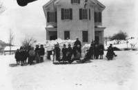 Class portrait in front of schoolhouse with sleds, Williamsville, Vt.