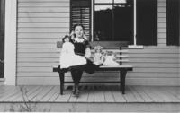 Ruth Wheeler sitting on a porch with dolls, Willimasville, Vt.