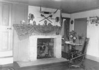 Interior of a residence with hearth, items on mantle place, and a wooden sitting chair, Dover?