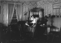 Mrs. Eddy's house interior with young woman at piano