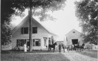 Man standing on a horse's back, with other horses and people, in front of farm in Windham County,Vermont
