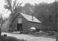 Exterior of a blcaksmith's shop with two employees, Jacksonville, Vt.