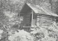 Man at small log cabin